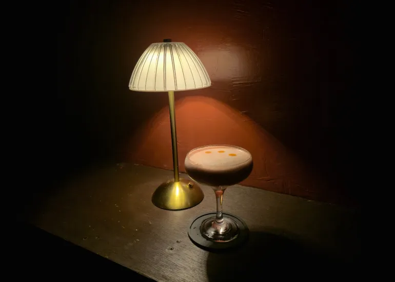 Baby It's Tonight cocktail at Blue Door 304, served in a coupe glass with a warm lamp glow
